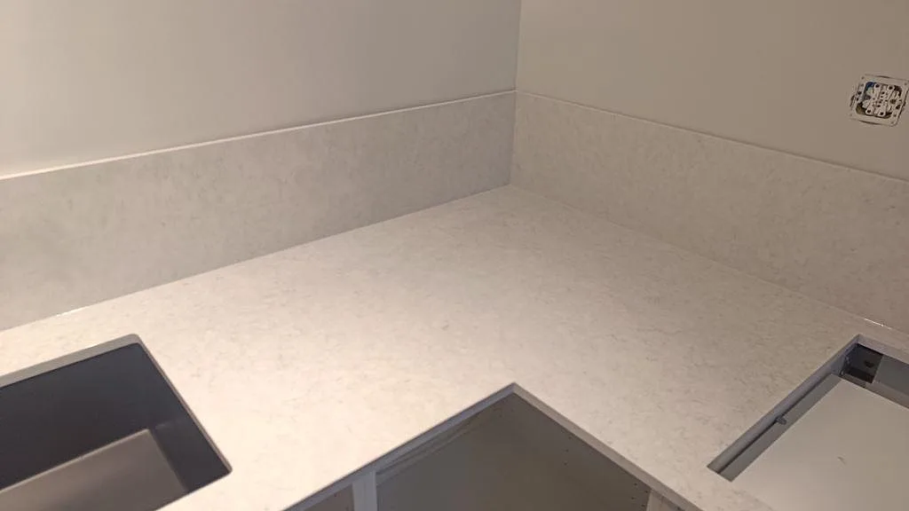 Hörnparti i polerad Silestone Snowy Ibiza med ljus köksbänkskiva, låg stänkkant och synlig ådring i Rydebäck.