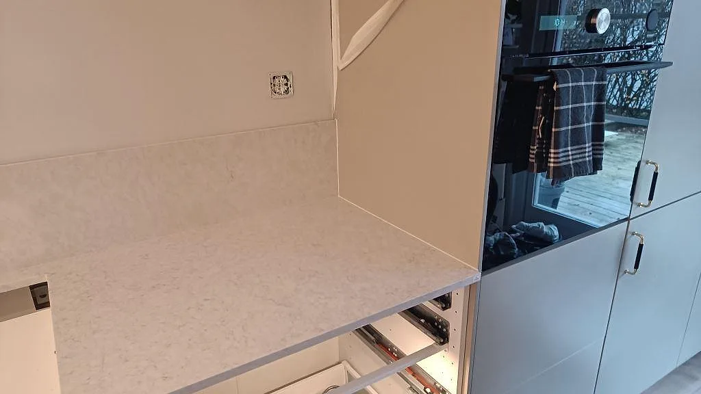 Höger bänkrad i polerad Silestone Snowy Ibiza intill högskåp och ugn i ett kök i Rydebäck.
