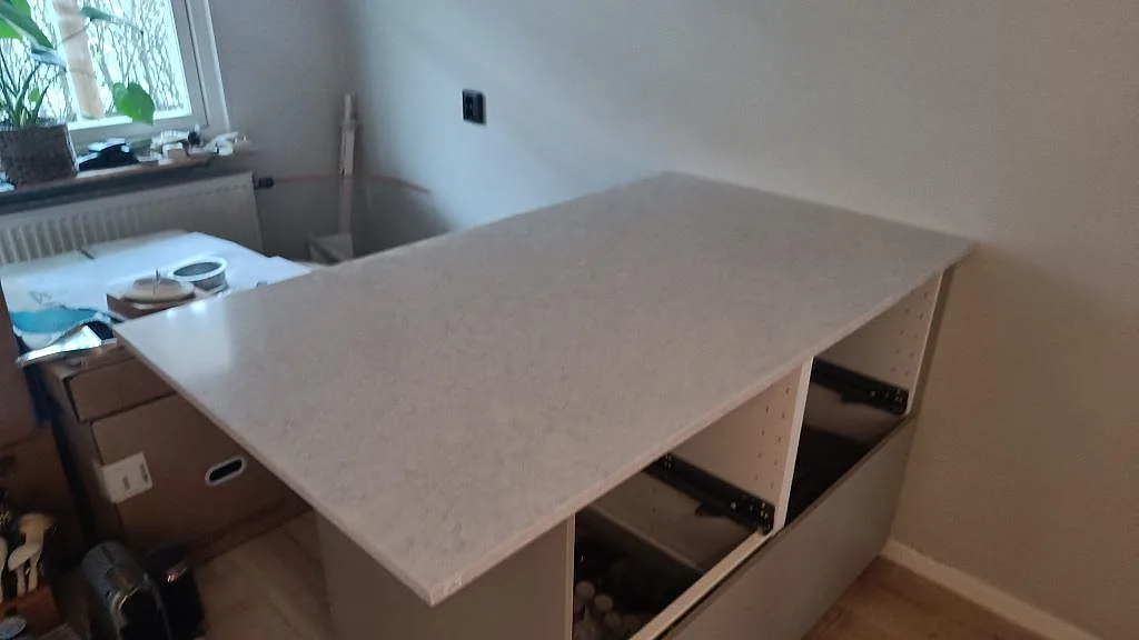 Extra arbetsyta i polerad Silestone Snowy Ibiza monterad över låga köksstommar i Rydebäck.