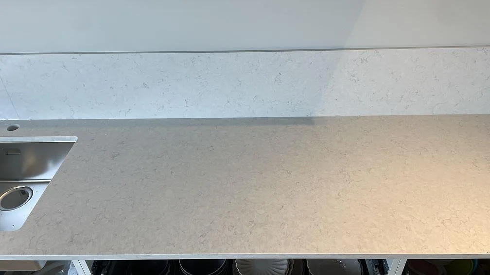 Bänkskiva i polerad Silestone Snowy Ibiza med diskho till vänster, låg stänkkant och ljus ådring i Rydebäck.