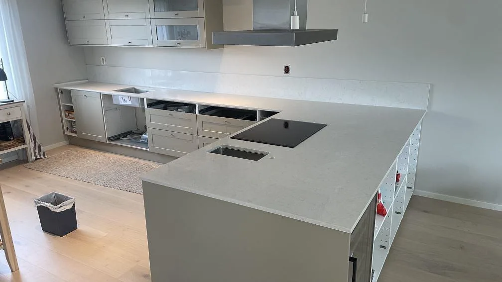 Köksbänkskiva och köksö i polerad Silestone Snowy Ibiza med underlimmad rostfri diskho, svart induktionshäll och låg stänkkant i Rydebäck.