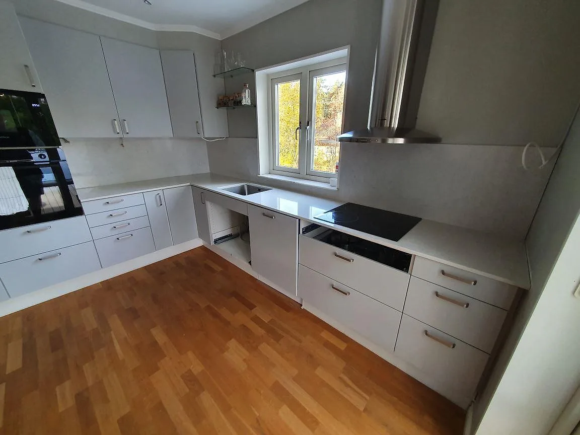 Kringgående köksbänkskiva i Silestone Snowy Ibiza, polerad, med underlimmad diskho och induktionshäll under montering i Saltsjö-Boo.
