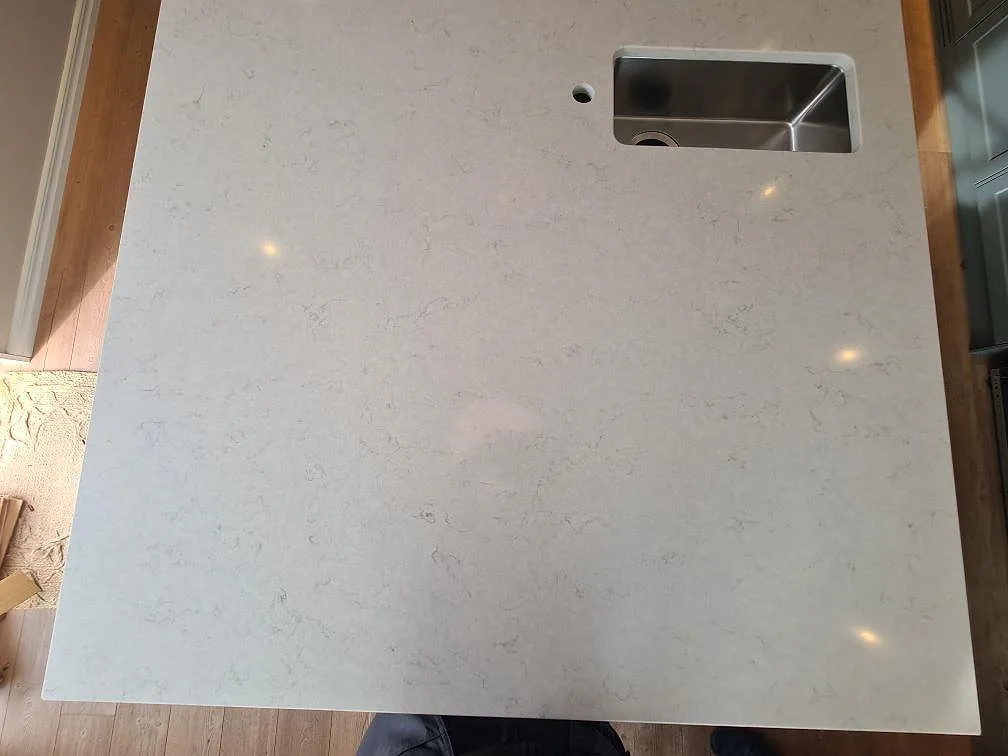 Närbild av polerad Silestone Snowy Ibiza komposit på köksö med rostfri diskho i Saltsjö Boo.