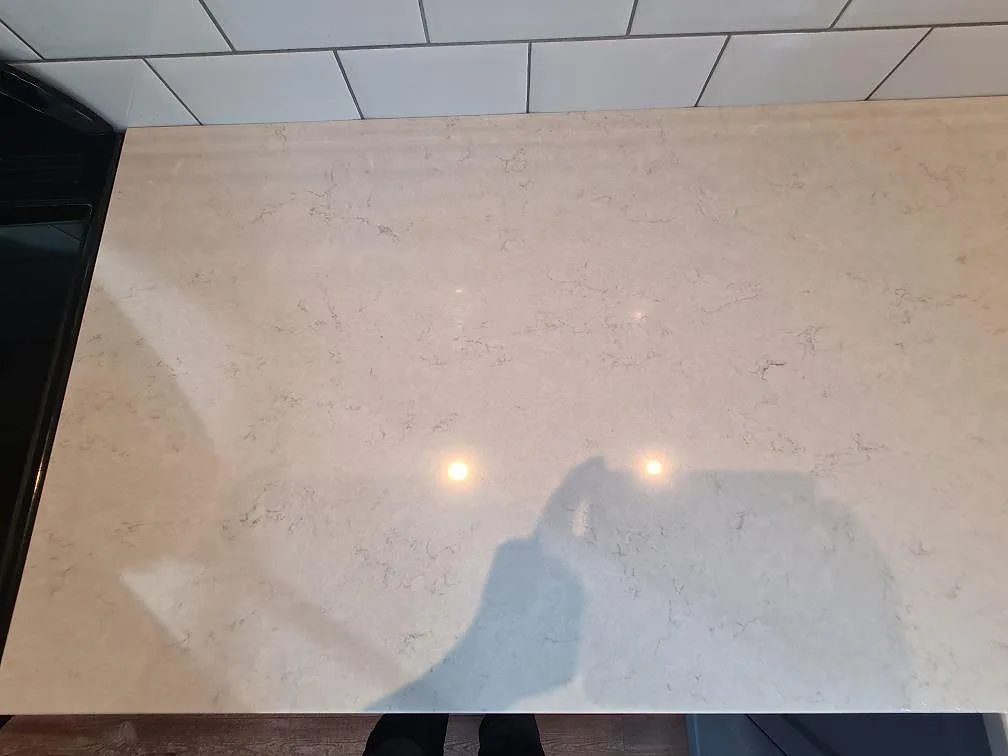 Ytdetalj av polerad Silestone Snowy Ibiza komposit med ljus ådring och kakel i Saltsjö Boo.