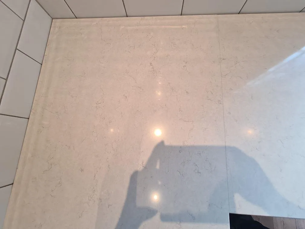 Hörndetalj i polerad Silestone Snowy Ibiza komposit med skarv mot vitt kakel i Saltsjö Boo.