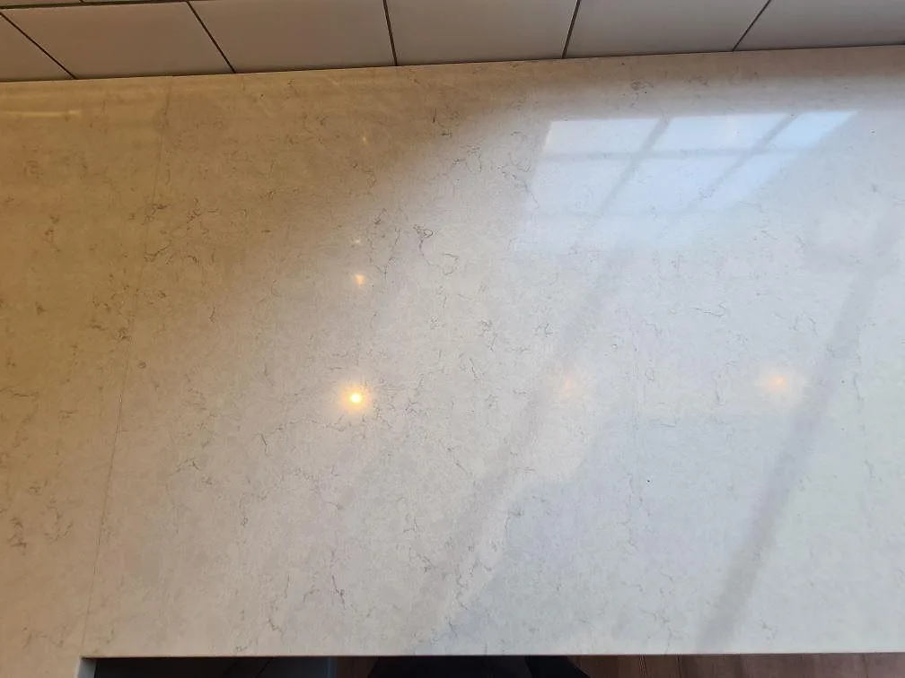 Närbild av polerad Silestone Snowy Ibiza bänkskiva med reflektion och ljus ådring i Saltsjö Boo.