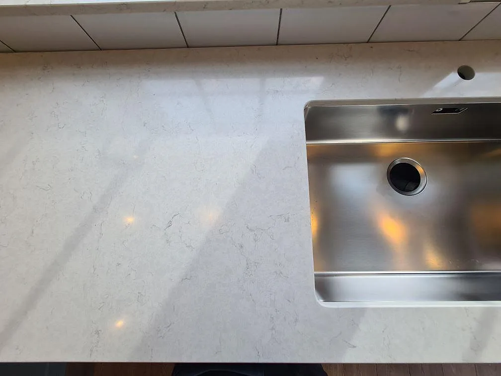 Detalj av rostfri underlimmad diskho i polerad Silestone Snowy Ibiza bänkskiva i Saltsjö Boo.