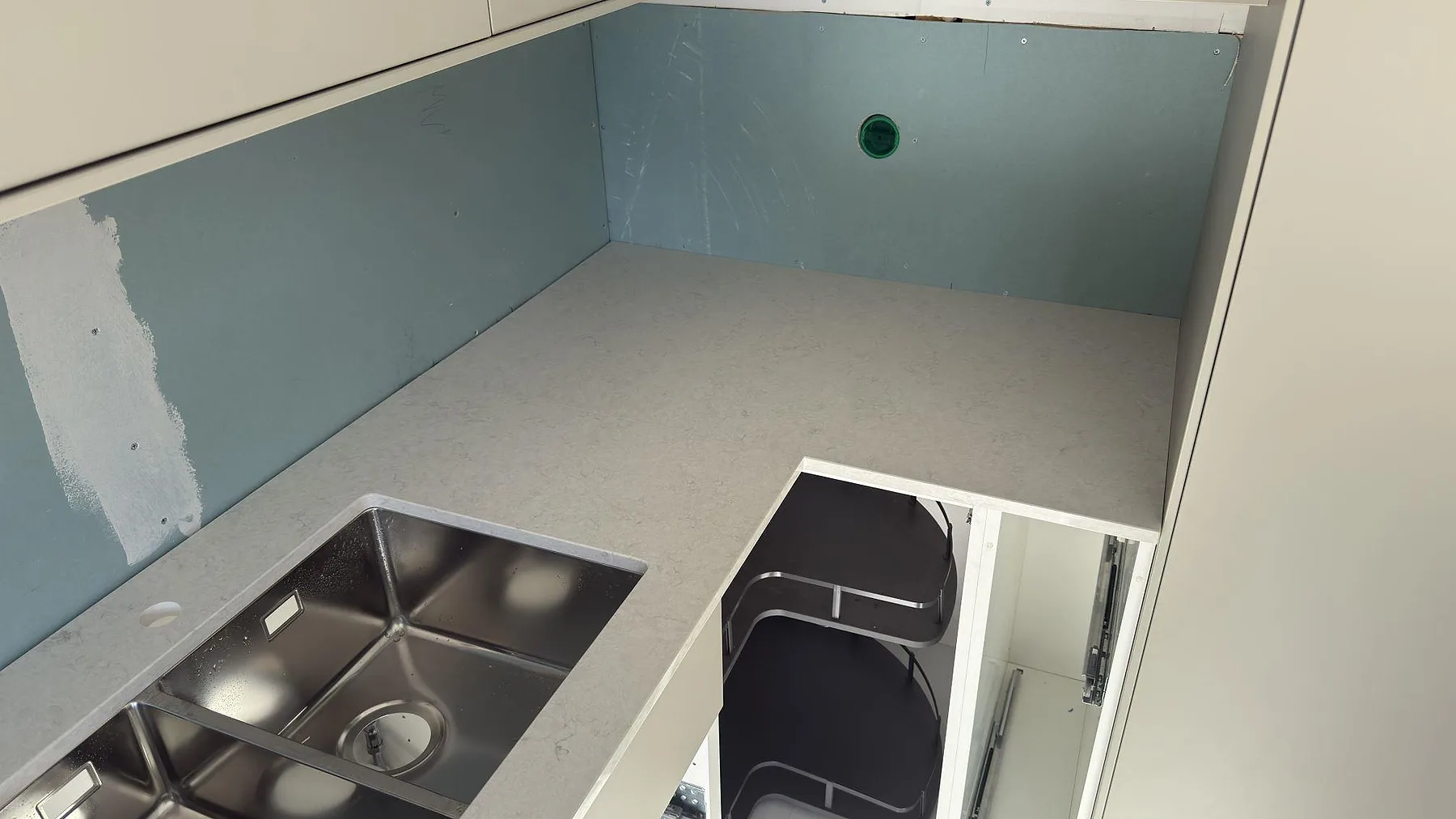 Hörndetalj av bänkskiva i Silestone Snowy Ibiza med underlimmad rostfri diskho med dubbla hoar i ett kök i Segeltorp.