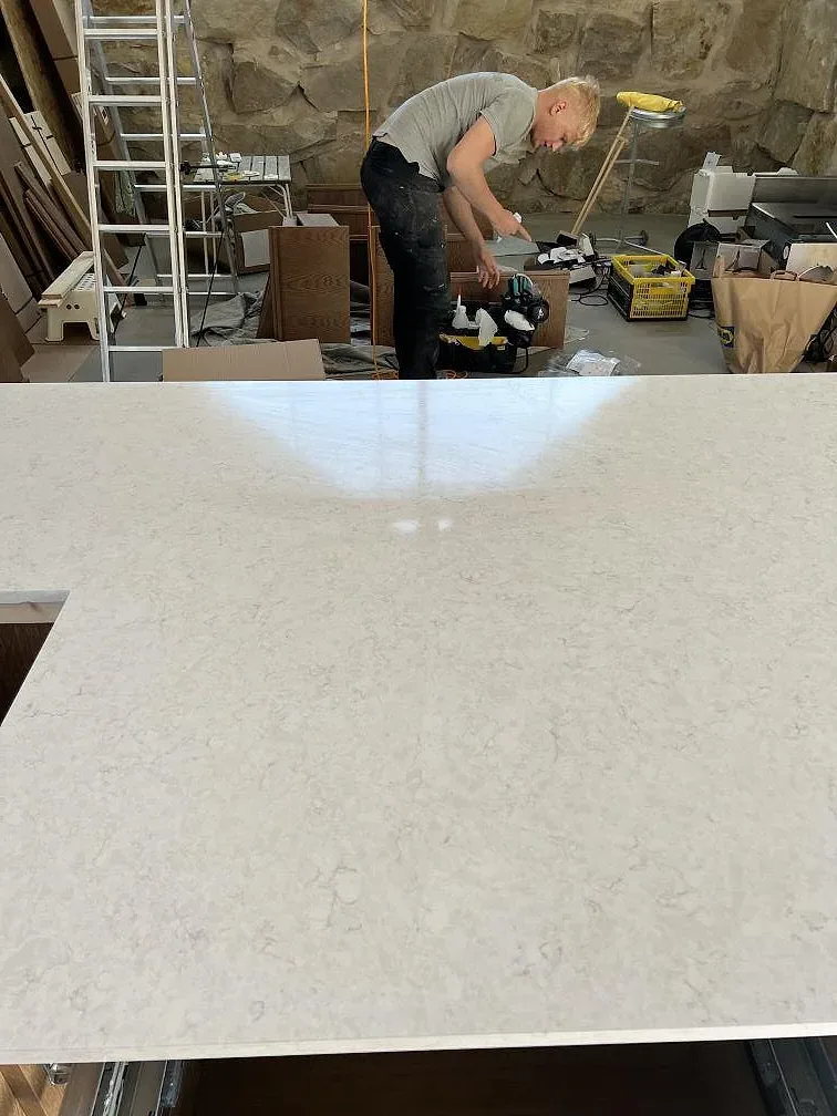 Stor yta av polerad Silestone Snowy Ibiza komposit med ljus ådring under montering i köket i Simrishamn.