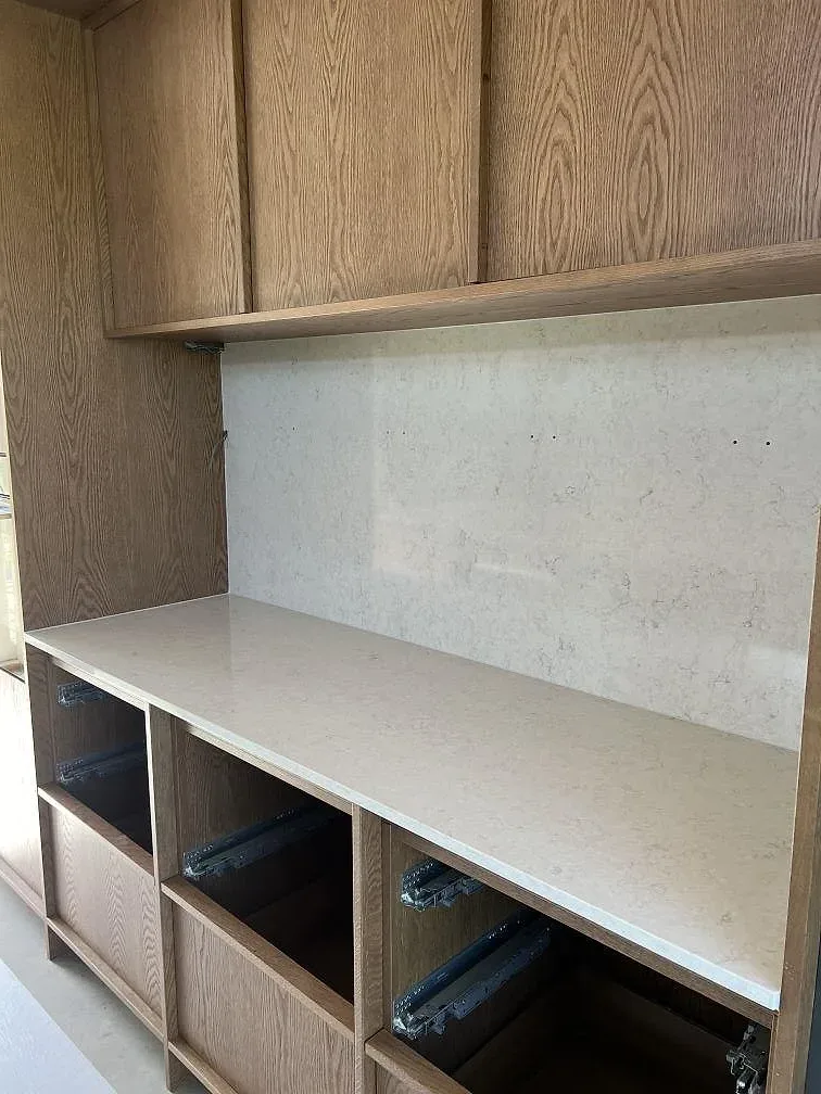 Sidovy av polerad Silestone Snowy Ibiza med ljus kompositådring och öppna trästommar under montering i Simrishamn.
