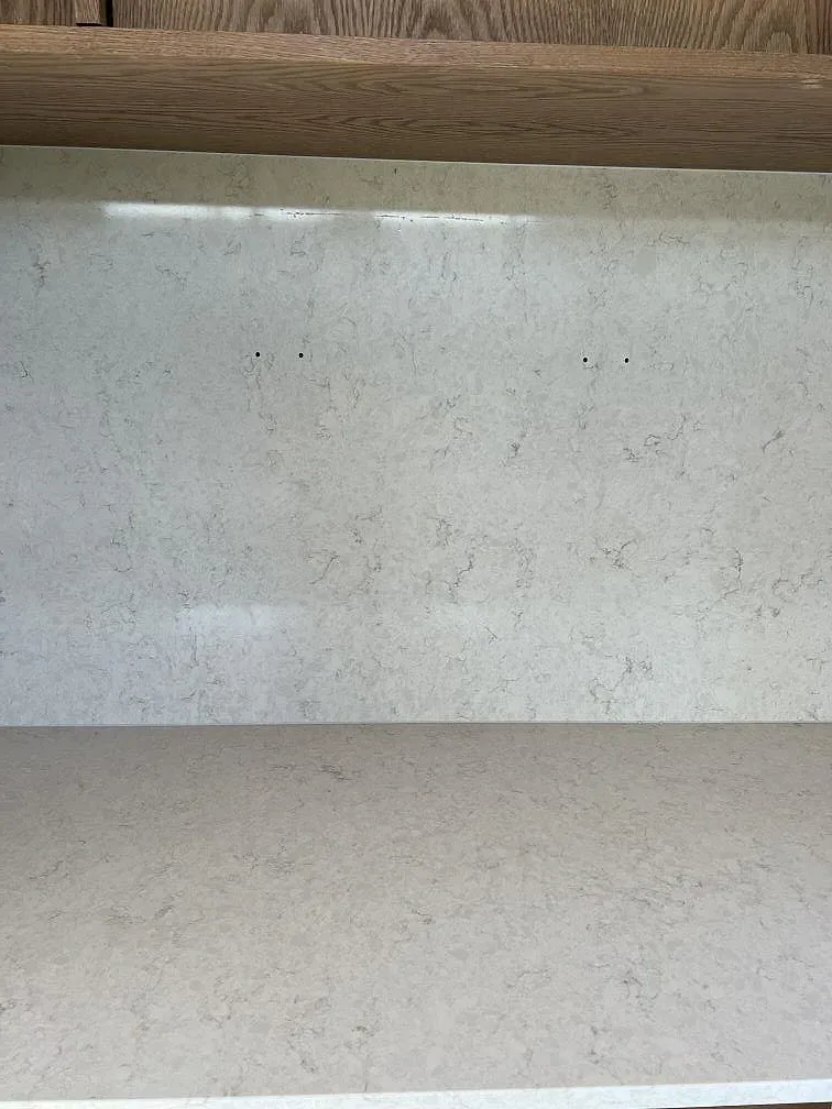 Ytdetalj på polerad Silestone Snowy Ibiza komposit med vertikalt stenparti och träinredning i Simrishamn.