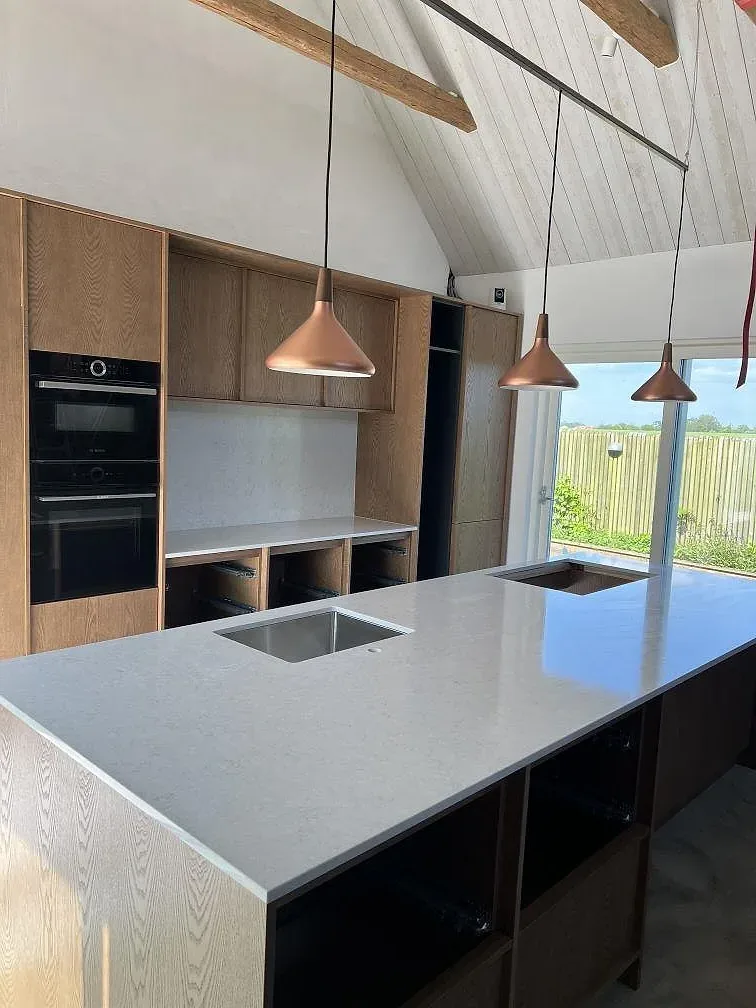 Köksbänkskiva i vit Silestone Snowy Ibiza, polerad komposit, med rostfri diskho och hällöppning i ett kök i Simrishamn.