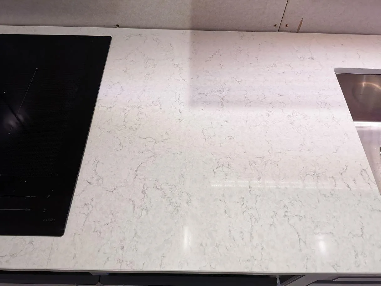 Bänkrad i polerad vit Silestone Snowy Ibiza med övermonterad induktionshäll och underlimmad rostfri diskho i ett kök i Sjöbo.