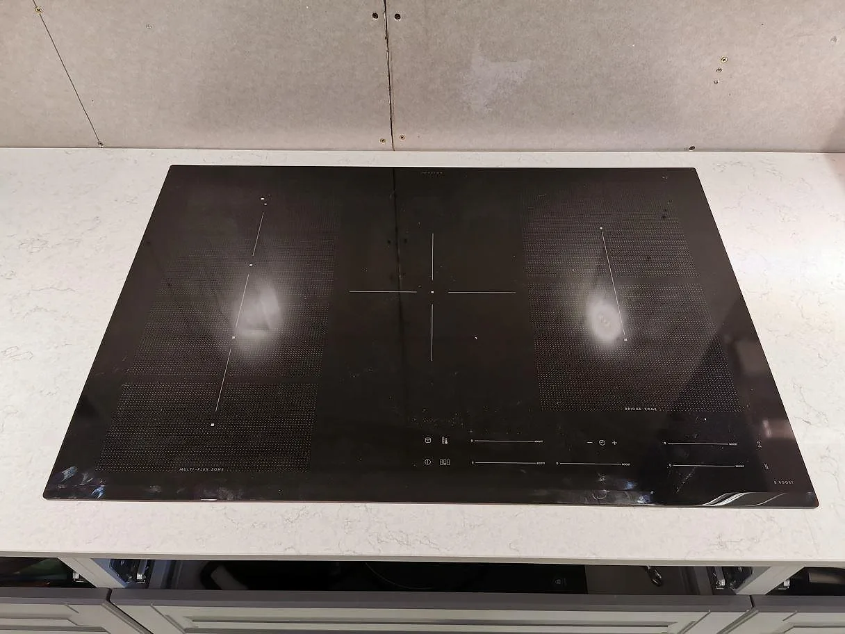 Övermonterad induktionshäll på polerad vit Silestone Snowy Ibiza köksbänkskiva i ett kök i Sjöbo.