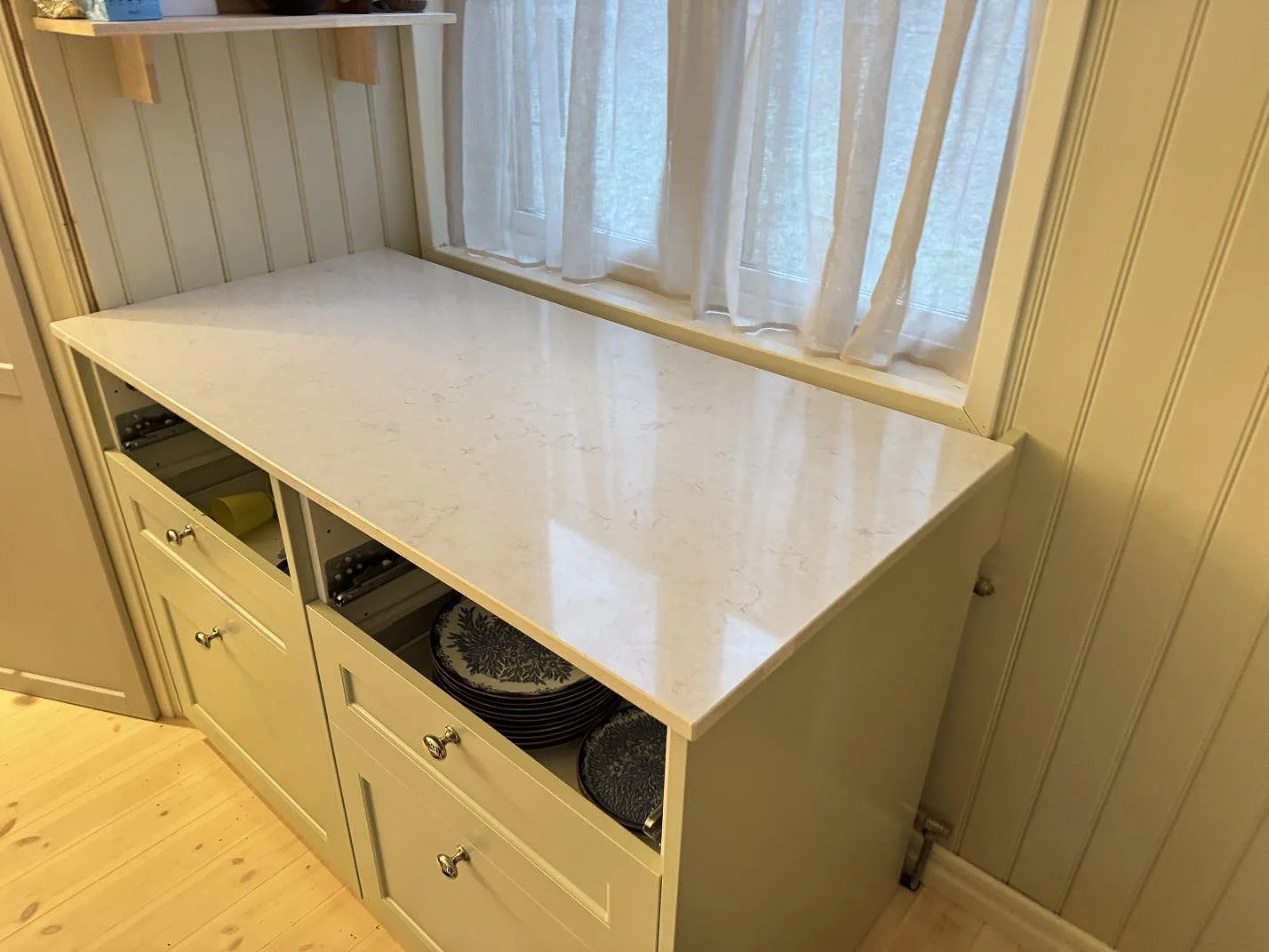 Ljus köksbänkskiva i Silestone Snowy Ibiza, 20 mm polerad komposit, monterad under fönster i Sjuntorp.