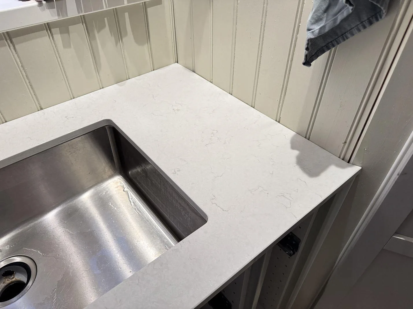 Detalj av vit Silestone Snowy Ibiza komposit runt rostfri diskho och väggpanel i Sjuntorp.