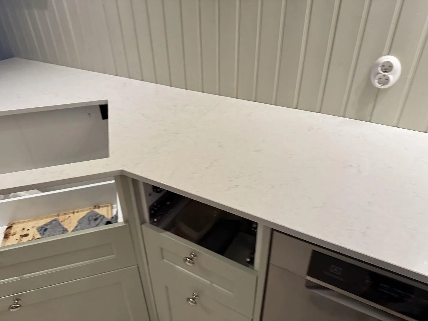 Hörnvy av polerad Silestone Snowy Ibiza bänkskiva med öppna stommar och ljus väggpanel i Sjuntorp.