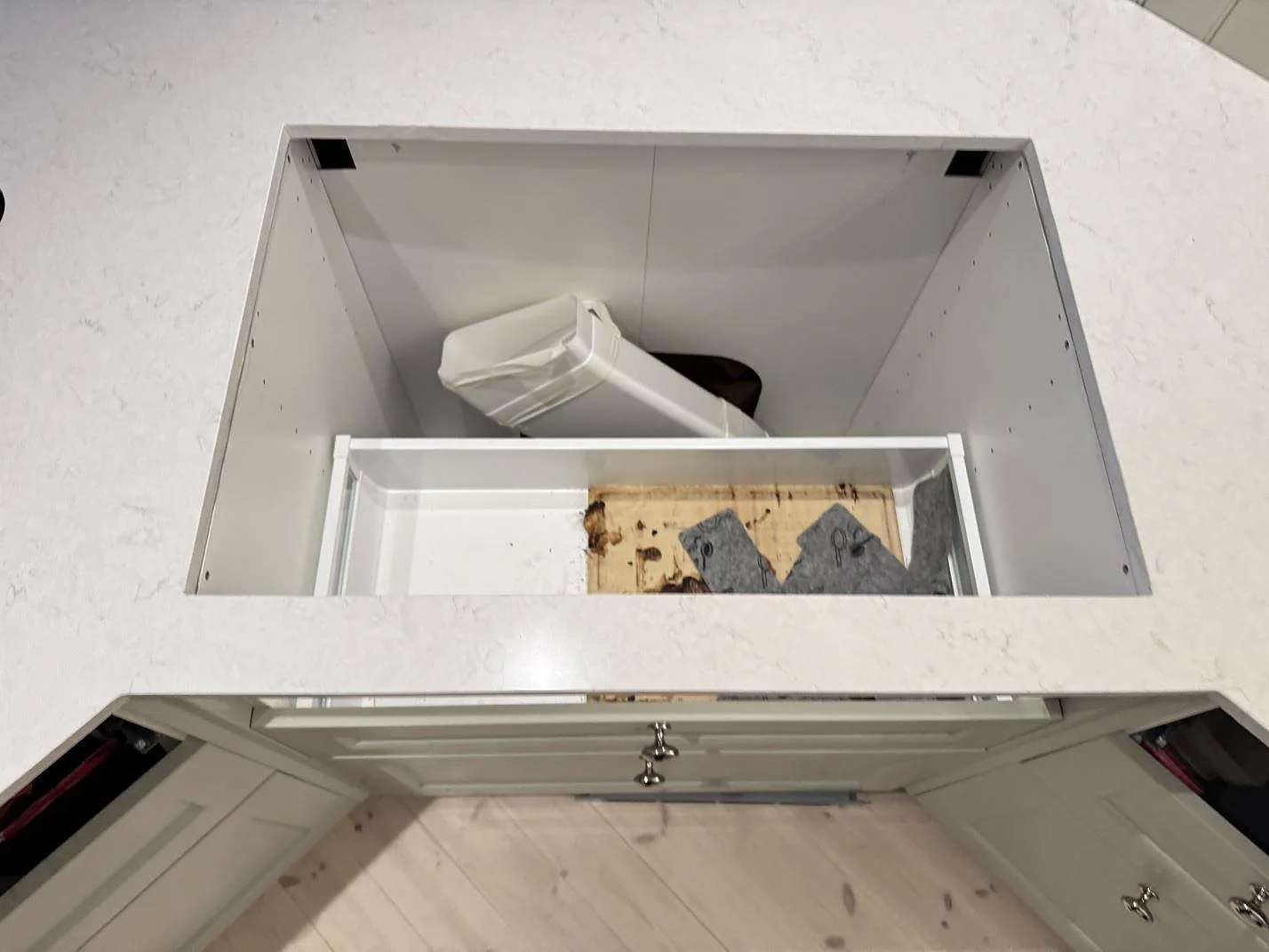 Polerad Silestone Snowy Ibiza bänkskiva med utskuren öppning i underskåp under montering i Sjuntorp.