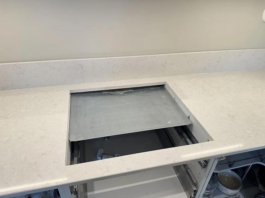 Ovanifrån av köksbänkskiva i vit Silestone Snowy Ibiza, polerad, med urtag för infälld häll och låg stänkkant i ett kök i Skanör.