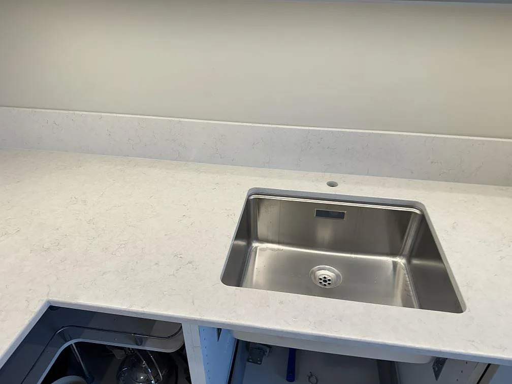 Underlimmad rostfri diskho i vit Silestone Snowy Ibiza, polerad, med separat hål för köksblandare i ett kök i Skanör.