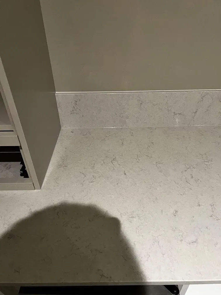 Detalj av polerad Silestone Snowy Ibiza med låg stänkkant, ljus ådring och telefonskugga i ett kök i Skummeslövsstrand.