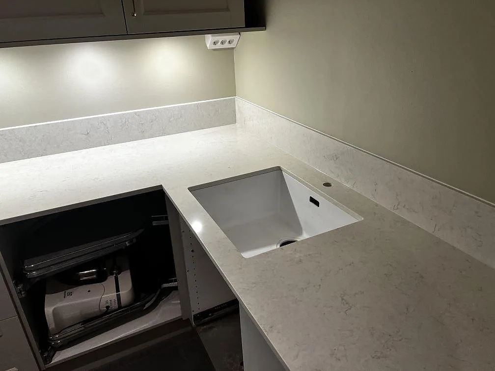 Polerad Silestone Snowy Ibiza som köksbänkskiva med underlimmad rostfri diskho och hällurtag i ett kök i Skummeslövsstrand.