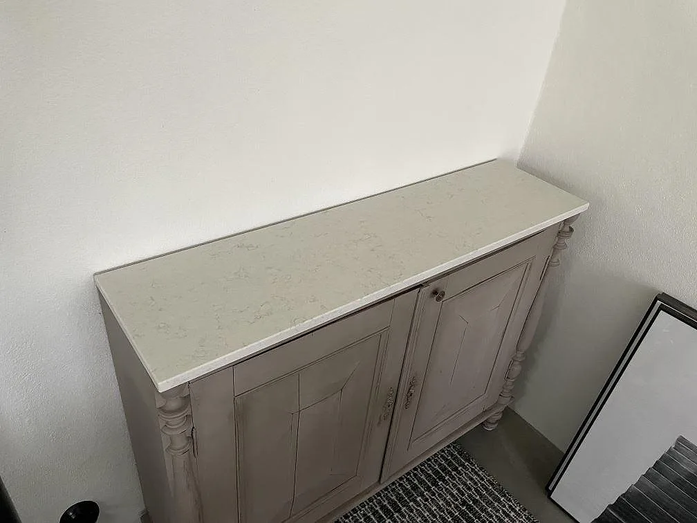Separat monterad bänkskiva i Silestone Snowy Ibiza på ett skåp, fotograferad i Skurup med den ljusa kompositens mönster synligt.
