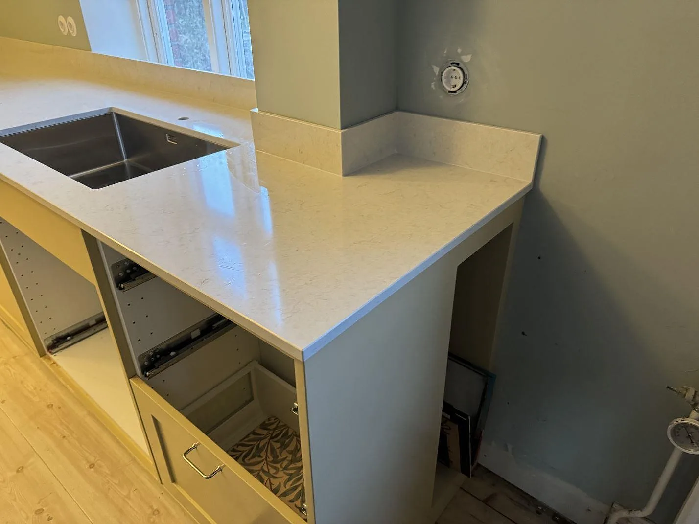 L-formad köksbänkskiva i ljus Silestone Snowy Ibiza, polerad, med rostfri diskho och uppvikt stänkkant i Skurup.