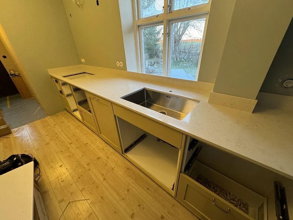Köksbänkskiva i polerad Silestone Snowy Ibiza med rostfri underlimmad diskho, urtag för häll och stänkskydd i Skurup.