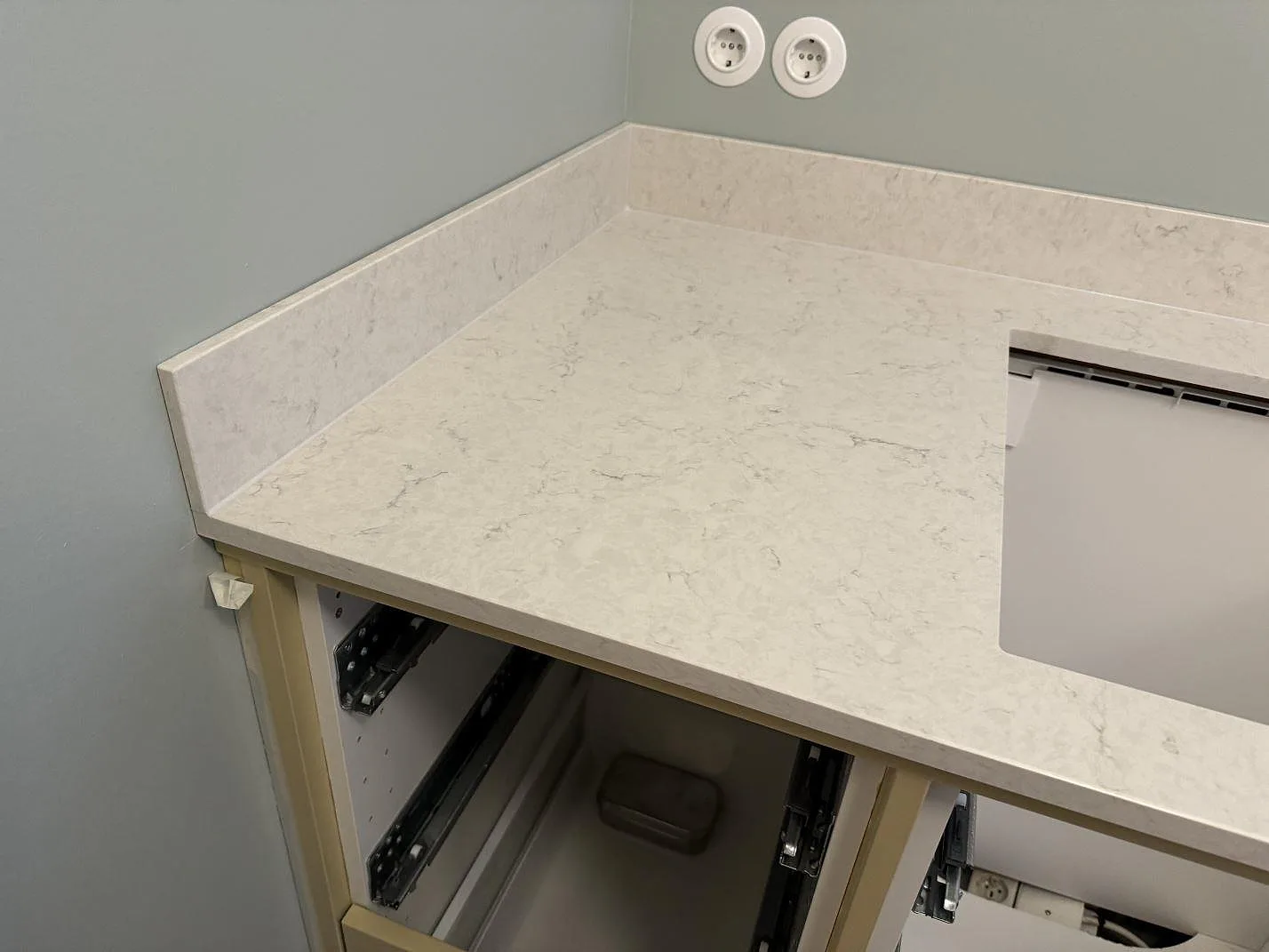 Hörn av köksbänkskiva i polerad Silestone Snowy Ibiza med stänkskydd och synliga köksstommar under montering i Skurup.