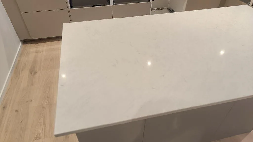 Köksö i vit Silestone Snowy Ibiza, polerad komposit, med tunn grå ådring i ett kök i Skurup.