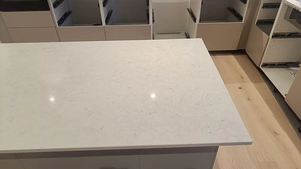Närbild på polerad Silestone Snowy Ibiza som köksö med ljus ådring och öppna lådsektioner i Skurup.