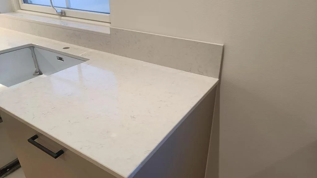 Bänkskiva i Silestone Snowy Ibiza med underlimmad diskho, stänkskydd och fönster i kök i Skurup.