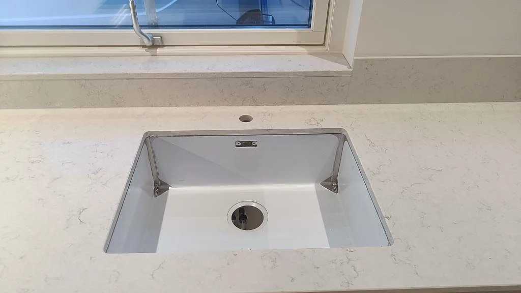 Underlimmad diskho i polerad Silestone Snowy Ibiza med 12 mm stänkkant under fönster i Skurup.