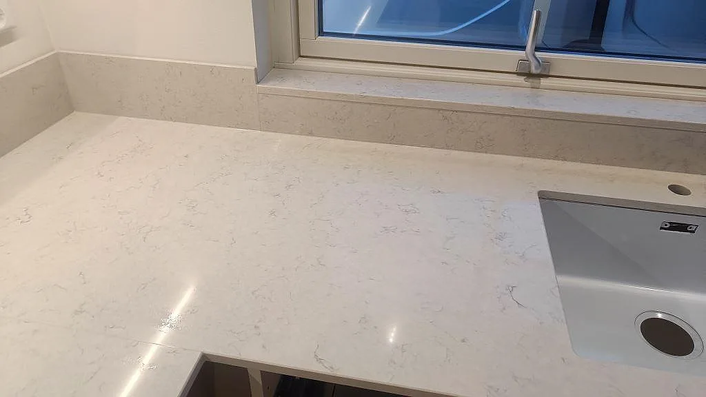 Sidovy av diskbänk i vit Silestone Snowy Ibiza med underlimmad diskho och stänkskydd i Skurup.
