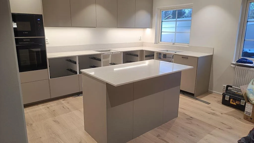 Polerad köksbänkskiva i vit Silestone Snowy Ibiza med köksö och bänkrader i ett kök i Skurup.