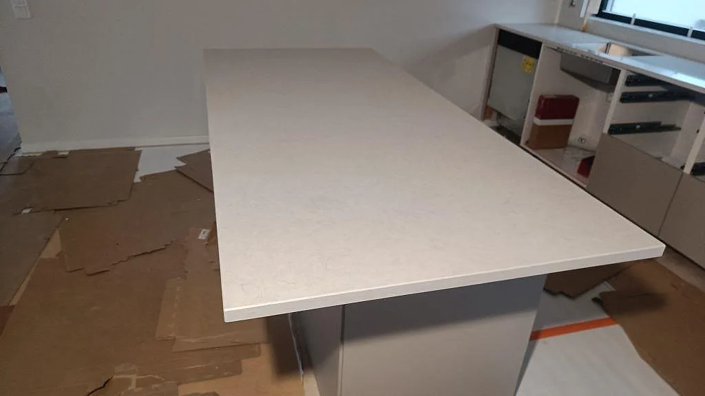 Stor köksö i Silestone Snowy Ibiza, polerad vit komposit, monterad på stommar i ett kök i Skurup.