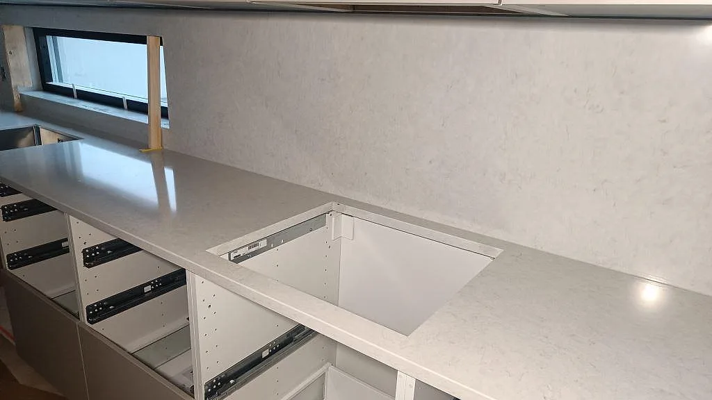 Detalj av polerad Silestone Snowy Ibiza runt ett rektangulärt urtag med matchande stänkskydd i köket i Skurup.