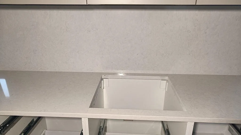 Frontal bild av Silestone Snowy Ibiza, polerad komposit, med urtag i bänkskivan och stor väggbeklädnad i Skurup.