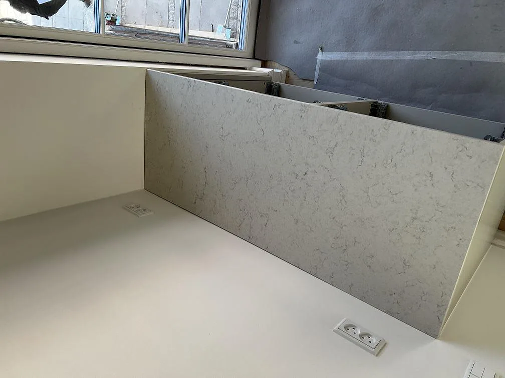 Vit Silestone Snowy Ibiza-bänkskiva, polerad, med uppvikt stänkskydd i samma sten i ett kök under montering i Slagelse.