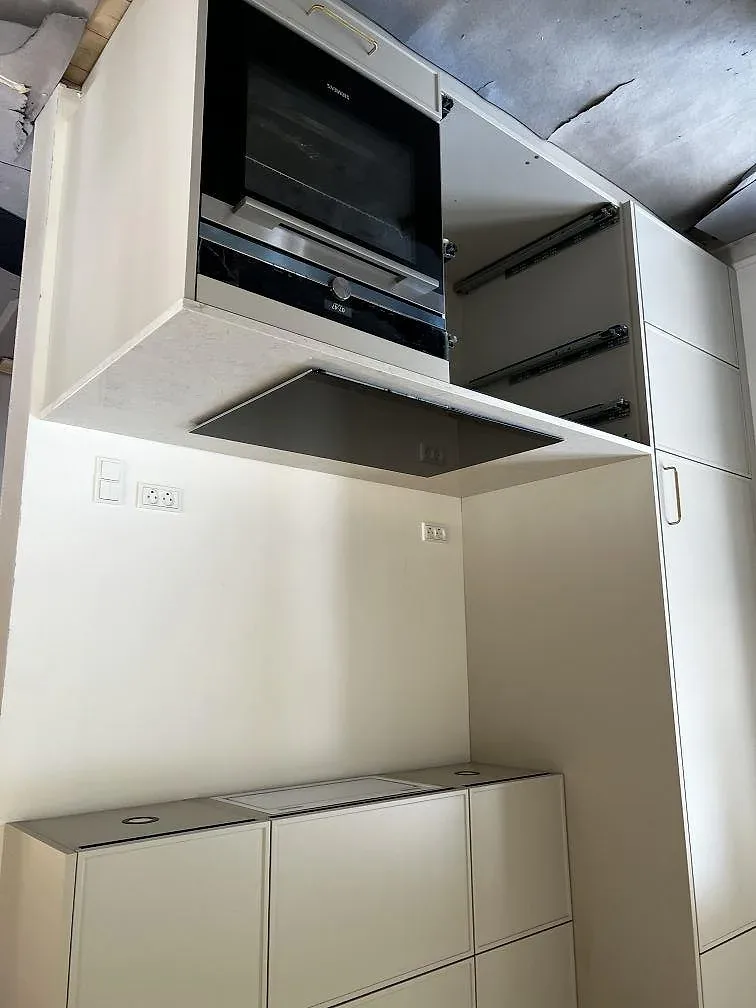 Köksbänkskiva i vit polerad Silestone Snowy Ibiza vid inbyggnadsugn och induktionshäll i ett kök i Slagelse.