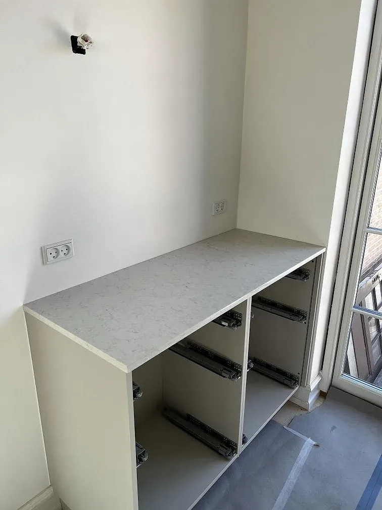 Köksbänkskiva i polerad Silestone Snowy Ibiza monterad på basskåp med fönsterbänk i ett kök i Slagelse.