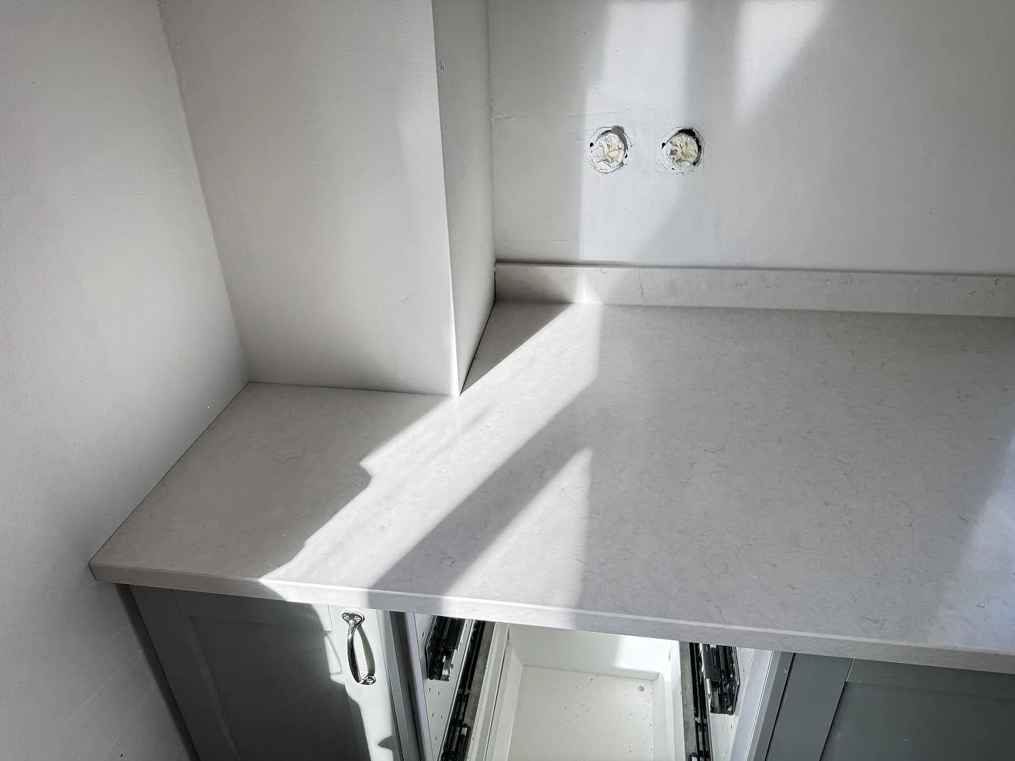 Vänstra delen av köksbänkskiva i polerad Silestone Snowy Ibiza, ljus kvartskomposit med låg stänkkant och ådring i Smygehamn.