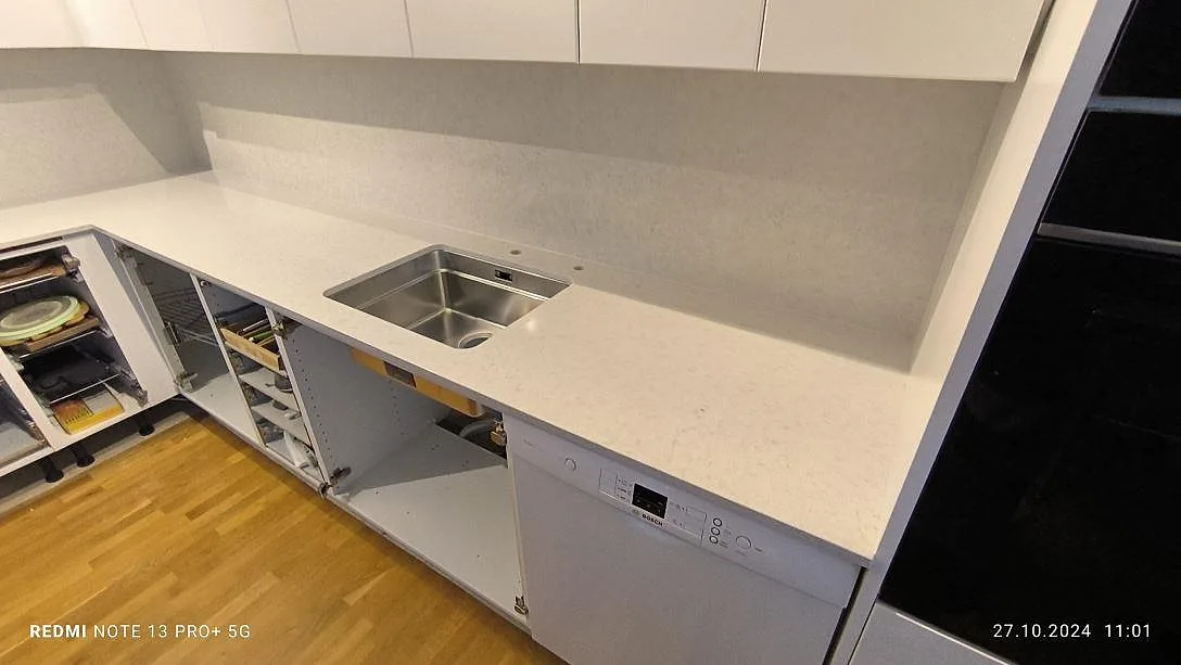 Närbild av polerad Silestone Snowy Ibiza som köksbänkskiva med synlig rostfri diskho och ljus stänkyta i Södertälje.