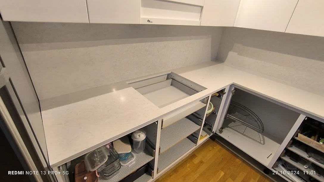 Köksbänkskiva i polerad Silestone Snowy Ibiza med öppet hällurtag, ljus stänkyta och öppna stommar under montering i Södertälje.