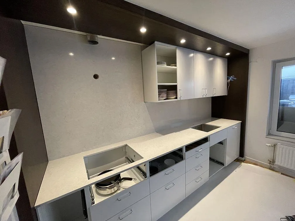 Köksbänkskiva i Silestone Snowy Ibiza, 20 mm polerad kvartskomposit, längs vägg med synliga urtag i ett kök i Södertälje.