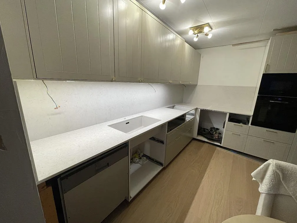 Polerad Silestone Snowy Ibiza som köksbänkskiva med öppning i arbetsytan och stänkskydd i ett L-format kök i Södertälje.
