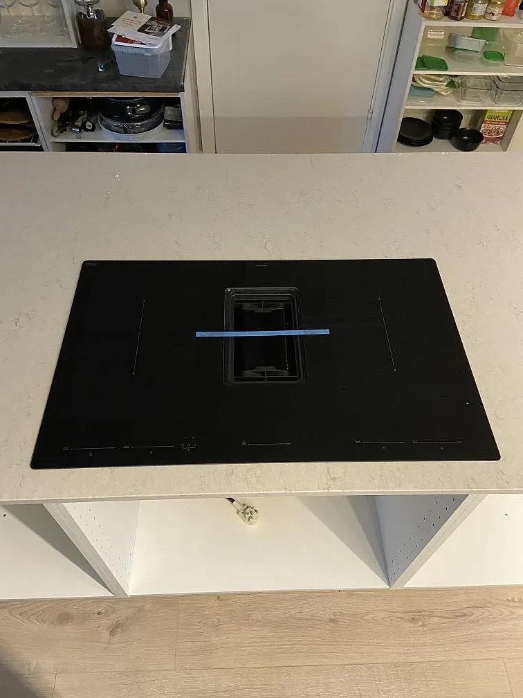 Sidobänkskiva i polerad Silestone Snowy Ibiza komposit intill högskåp och rå vägg i kök i Staffanstorp.