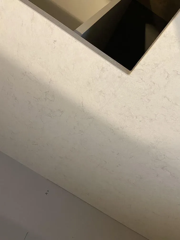 Köksbänkskivor i polerad Silestone Snowy Ibiza komposit längs fönstervägg och öppna stommar under pågående inredning i Staffanstorp.