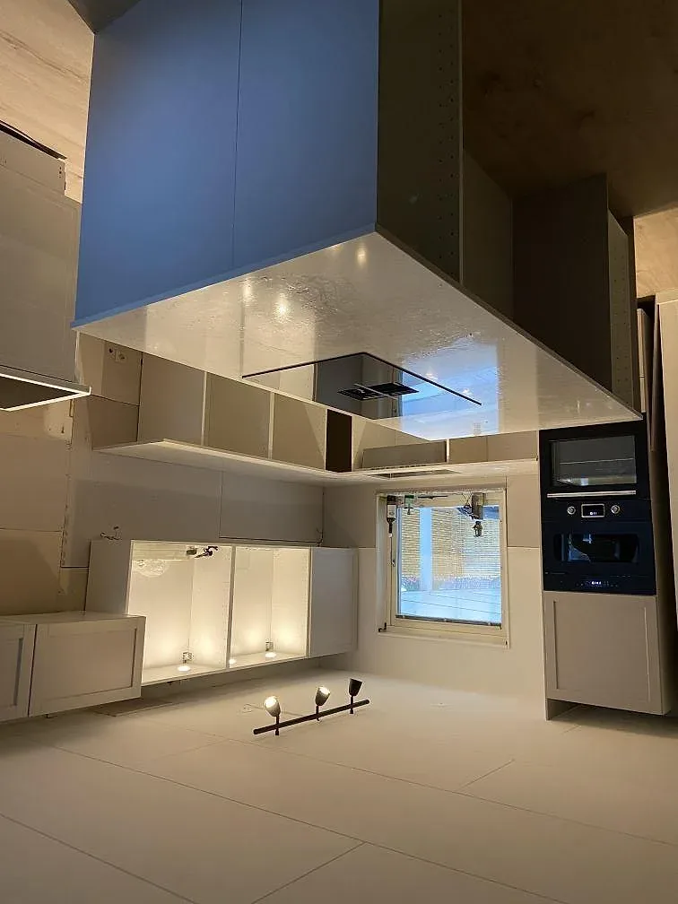 Köksbänkskiva i vit Silestone Snowy Ibiza komposit, polerad, på köksö med svart övermonterad spishäll i Staffanstorp.